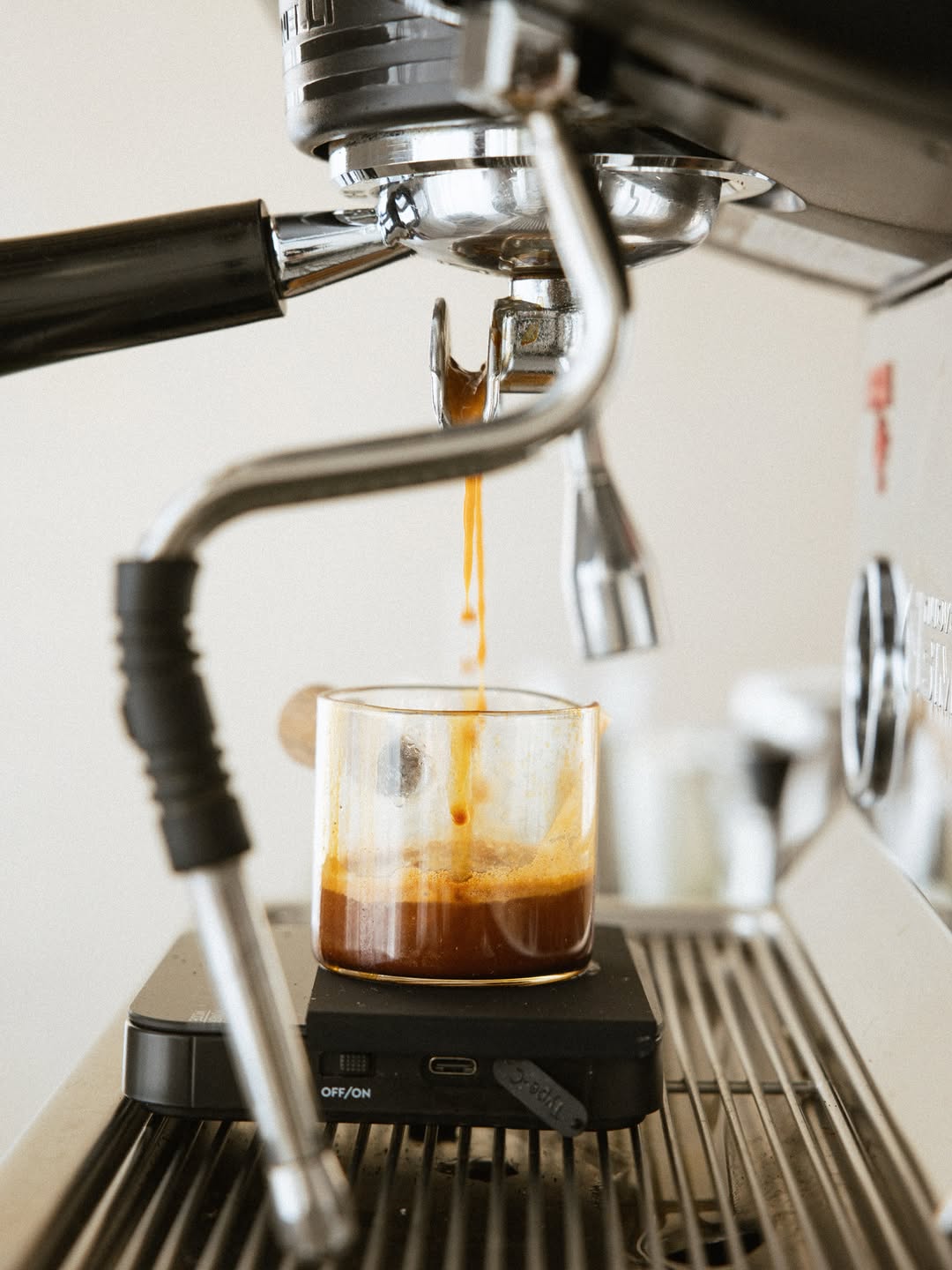 Espresso pouring from a machine into a glass on a scale